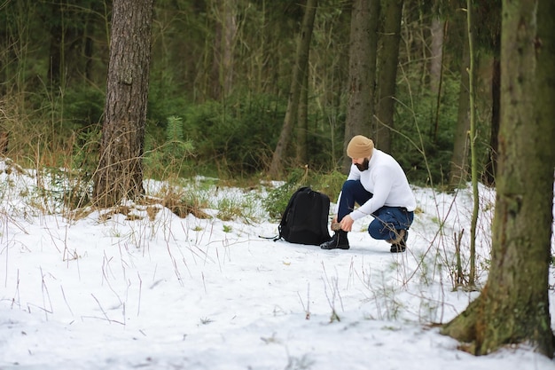 Outdoor portrait of handsome man in coat and scurf. Bearded man in the winter woods.