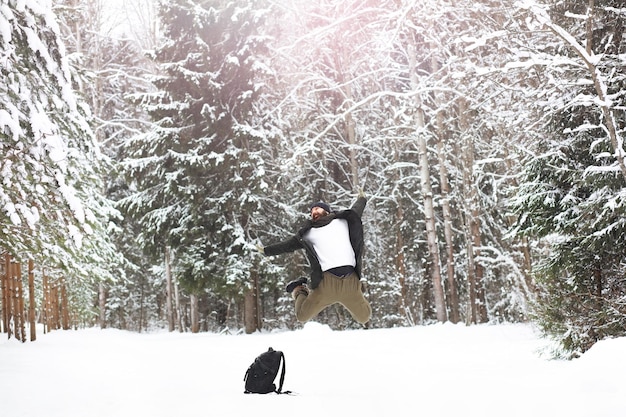 Outdoor portrait of handsome man in coat and scurf bearded man
in the winter woods