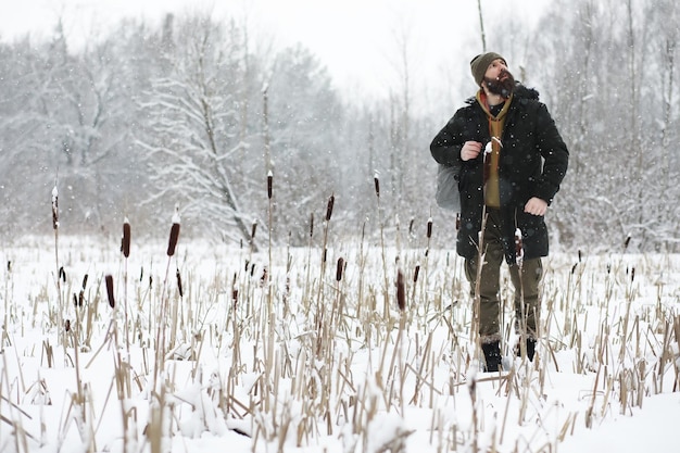 Outdoor portrait of handsome man in coat and scurf Bearded man in the winter woods