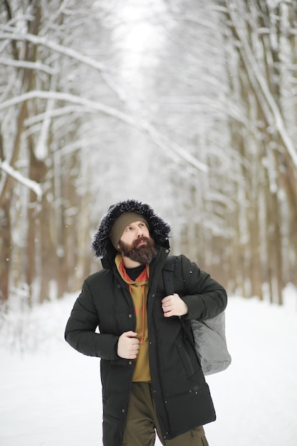 Outdoor portrait of handsome man in coat and scurf Bearded man in the winter woods