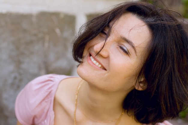 Outdoor portrait of happy brunet woman with closed eyes