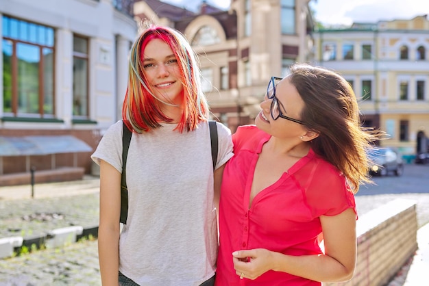 Outdoor portrait of happy mother and daughter of teenager 16, 17 years old hugging together. Family, lifestyle, mother's day