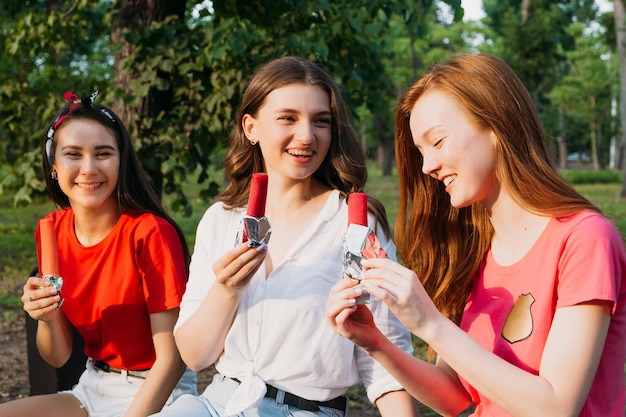 Ritratto all'aperto di tre giovani donne felici in possesso di un gelato in estate parco sfondo tre