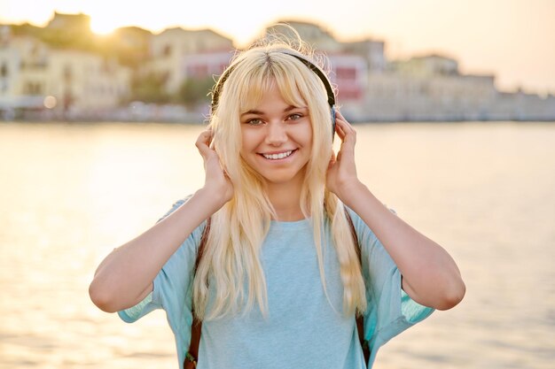 Outdoor portrait of happy young blonde woman wearing headphones