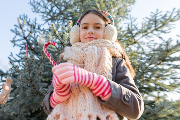 Foto ritratto all'aperto della bambina vicino all'albero di natale