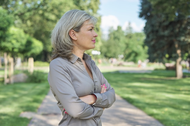 Outdoor portrait of positive mature middle-aged woman