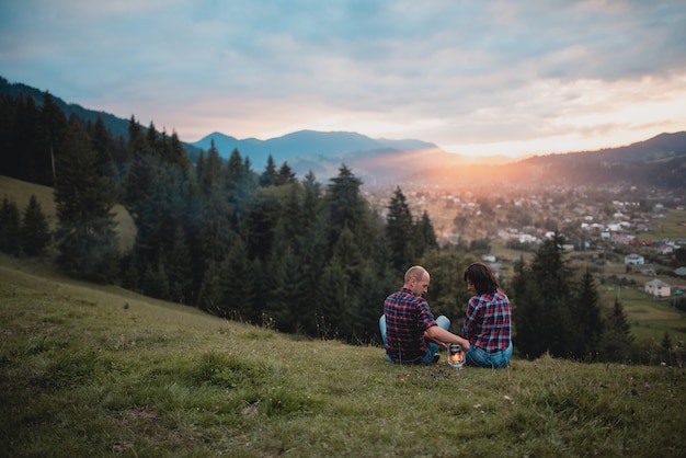 Outdoor portrait of romantic couple picnic in mountain view at sunset