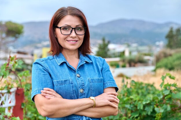 Outdoor portrait of smiling successful mature woman with folded hands