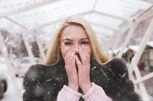 雪片とホリデーフェアで歩いている驚いた若い女性の屋外の肖像画