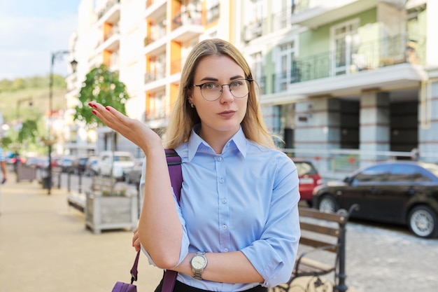 Outdoor portrait of talking young business woman in city female looks at web camera