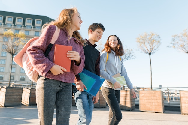 Outdoor portrait of teenage students with backpacks walking