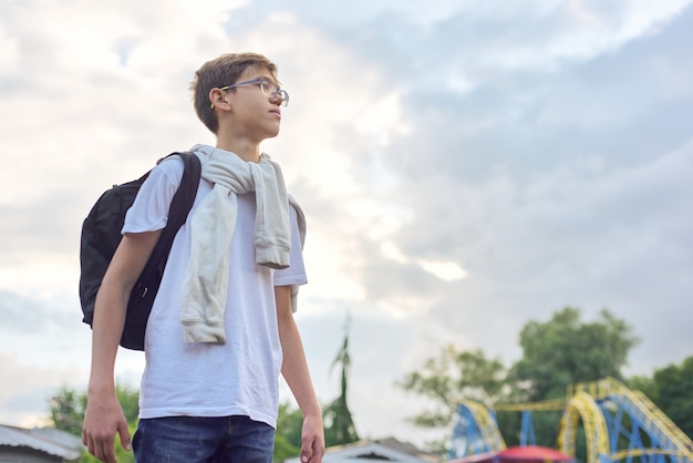 メガネのバックパックを持つ10代の少年の屋外のポートレート