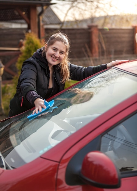 Outdoor portrait of woman washing car windscreen