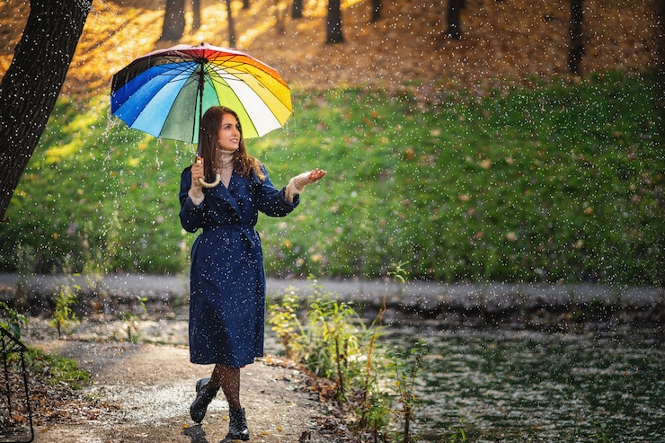 Photo outdoor portrait of young beautiful happy smiling girl holding umbrella and posing under rain in the autumn park