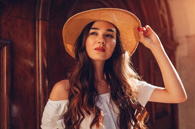 Outdoor portrait of young beautiful woman with long hair wearing straw hat. Fashion model. Close-up