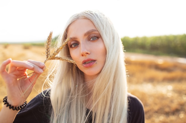 Outdoor portrait of young beauty  blonde girl holding some wheat spikes.