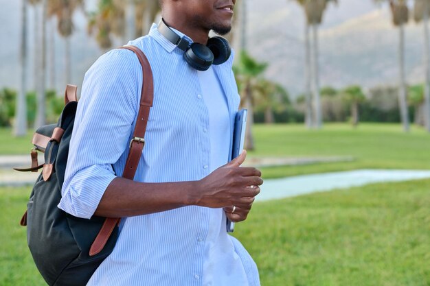 Outdoor portrait of young man with laptop headphones and backpack