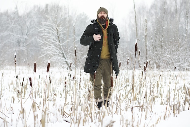 Outdoor Portret van knappe man in jas en scurf. Bebaarde man in het winterbos.