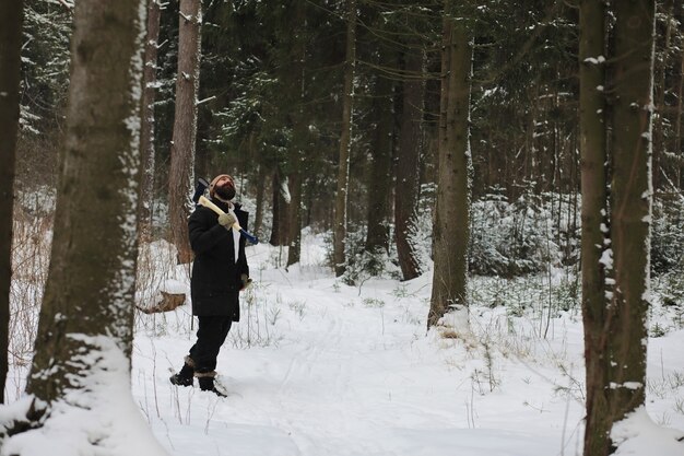 Outdoor Portret van knappe man in jas en scurf. Bebaarde man in het winterbos.