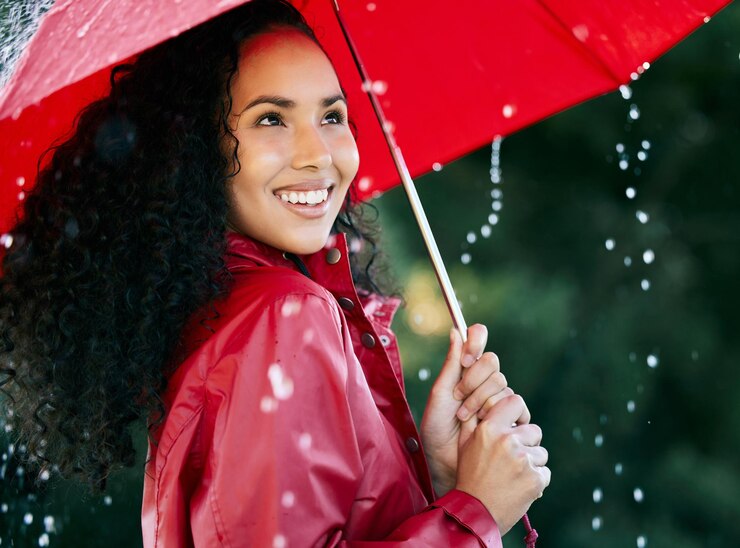 Photo outdoor rain and happy woman with umbrella for cheerful weather protection or life insurance in park cover water and african person with shield for safety storm or winter day in jamaica