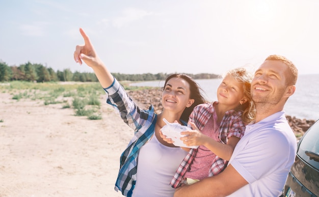 Outdoor recreation leisure for family. birthday gift. a man and a woman and girl launch a radio-controlled aircraft or a drone or a helicopter into the sky. and they run it together.