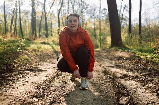 Обувь для фитнеса на открытом воздухе и спортивная женщина начинают кардиотренировку в лесу