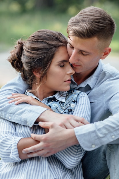 Outdoor shot of young happy couple in love sitting on grass on nature.