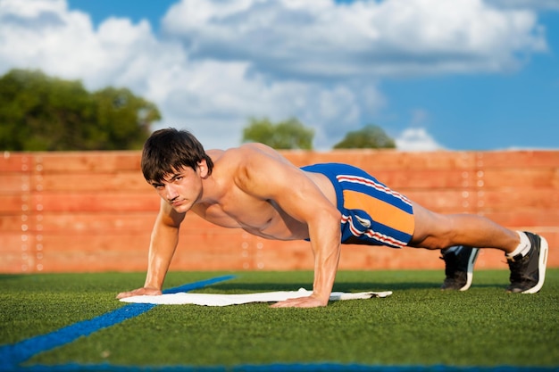 Outdoor sport fitness training Handsome Young Men Doing Pushups Outdoors in the Sport Field on a Sunny day