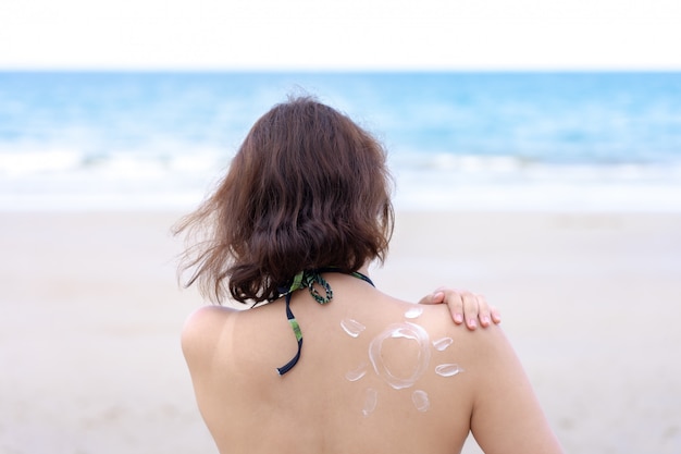 Outdoor summer portrait of Young Asian tan woman wearing bikini sitting on the beach