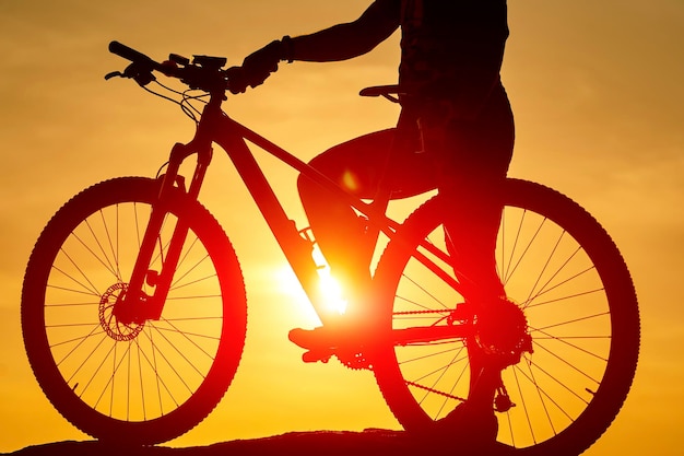 屋外の日没の自転車ライダー旅行のサイクリストのシルエット