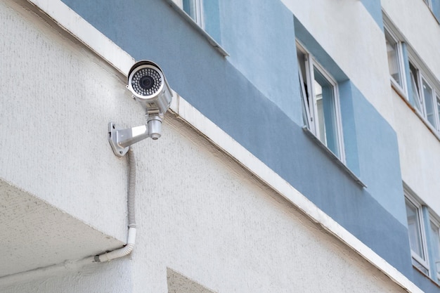 Outdoor surveillance camera on a blue white wall of an apartment building in a residential area of the city during the day