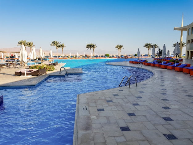 여름 해변 호텔 리조트에서 일광욕 침대가 많은 야외 수영장