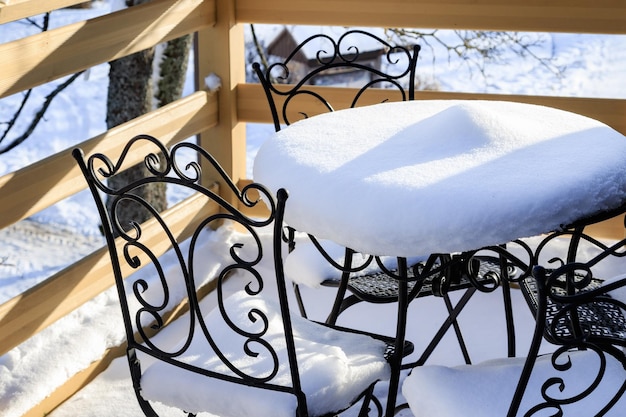 Tavolo e sedie da esterno ricoperti di neve dopo la prima nevicata