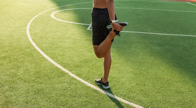 Outdoor training. Attractive woman stretches leg before training