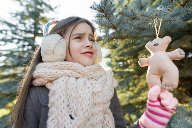 クリスマスツリーの近くの笑顔の女の子の屋外の冬のポートレート