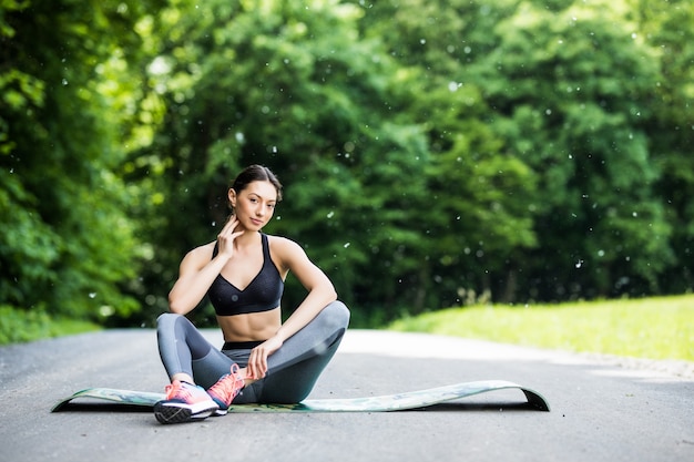 Outdoor workout woman. Fitness woman runner sitting after training outside in park