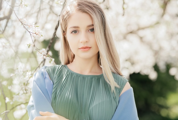 Outdoors fashion photo of beautiful young lady in the garden of apple blossoms