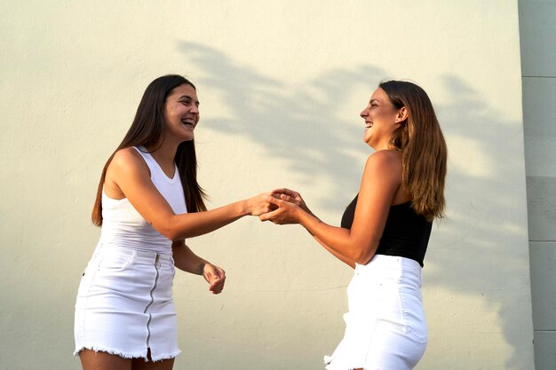 Foto ritratto di moda all'aperto delle giovani ragazze belle migliori amiche in un abbraccio amichevole che camminano in città.