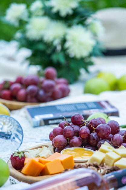 Outdoors picnic in a lush green park with a tasty croissant fruits donuts and wine on grass