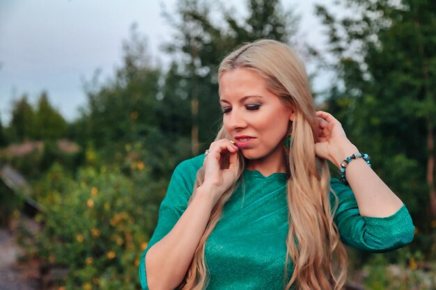 Outdoors portrait adult woman on nature walking in summer forest of dusk. Dreamer lady in wear walk evening on parkland. Positive emotion of female on park at dawn