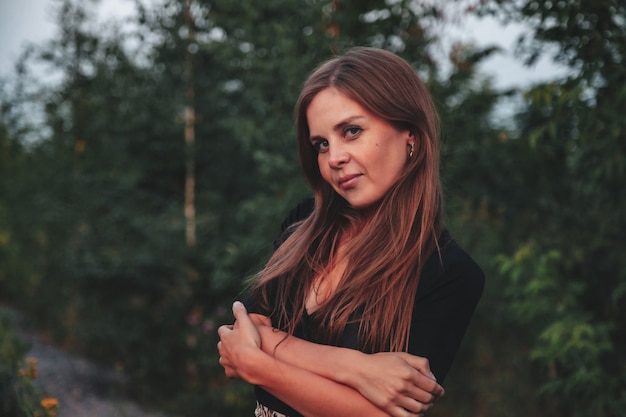 Outdoors portrait adult woman on nature walking in summer forest of dusk. Dreamer lady in wear walk evening on parkland. Positive emotion of female on park at dawn