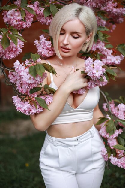 Outdoors portrait of Beautiful woman in pink blossoms on spring day