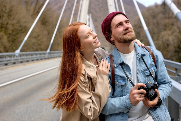 Outdoors portrait of man and woman in casual warm outfits having a walk on bridge