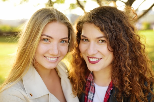 Outdoors portrait of two delightful young woman