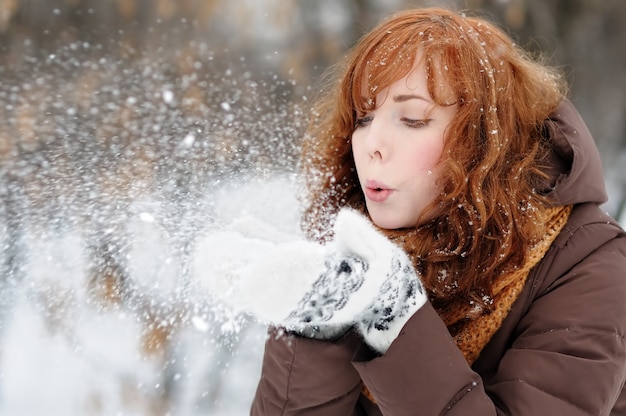 冬で楽しんでいる若い美しい女性の屋外のポートレート