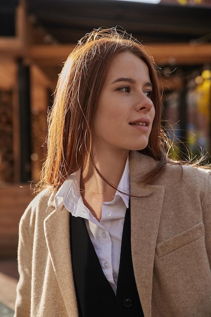 Outdoors portrait of young caucasian red headed girl in coat with long hair