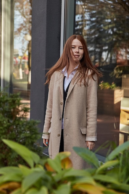 Outdoors portrait of young caucasian red headed girl in coat with long hair