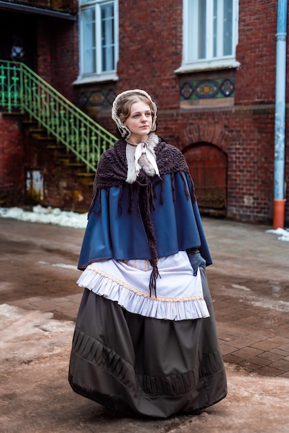 Outdoors portrait of a young victorian woman walking old city