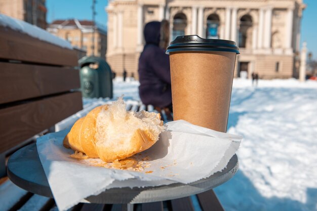 行くベンチコーヒーとクロワッサンのクローズアップと屋外テーブル