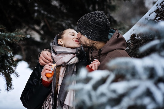 Outdoors Valentines Day Date Ideas for Couples Winter love story Cold season dating for couples Young couple in love eating oranges hugging and kissing in winter city street and park